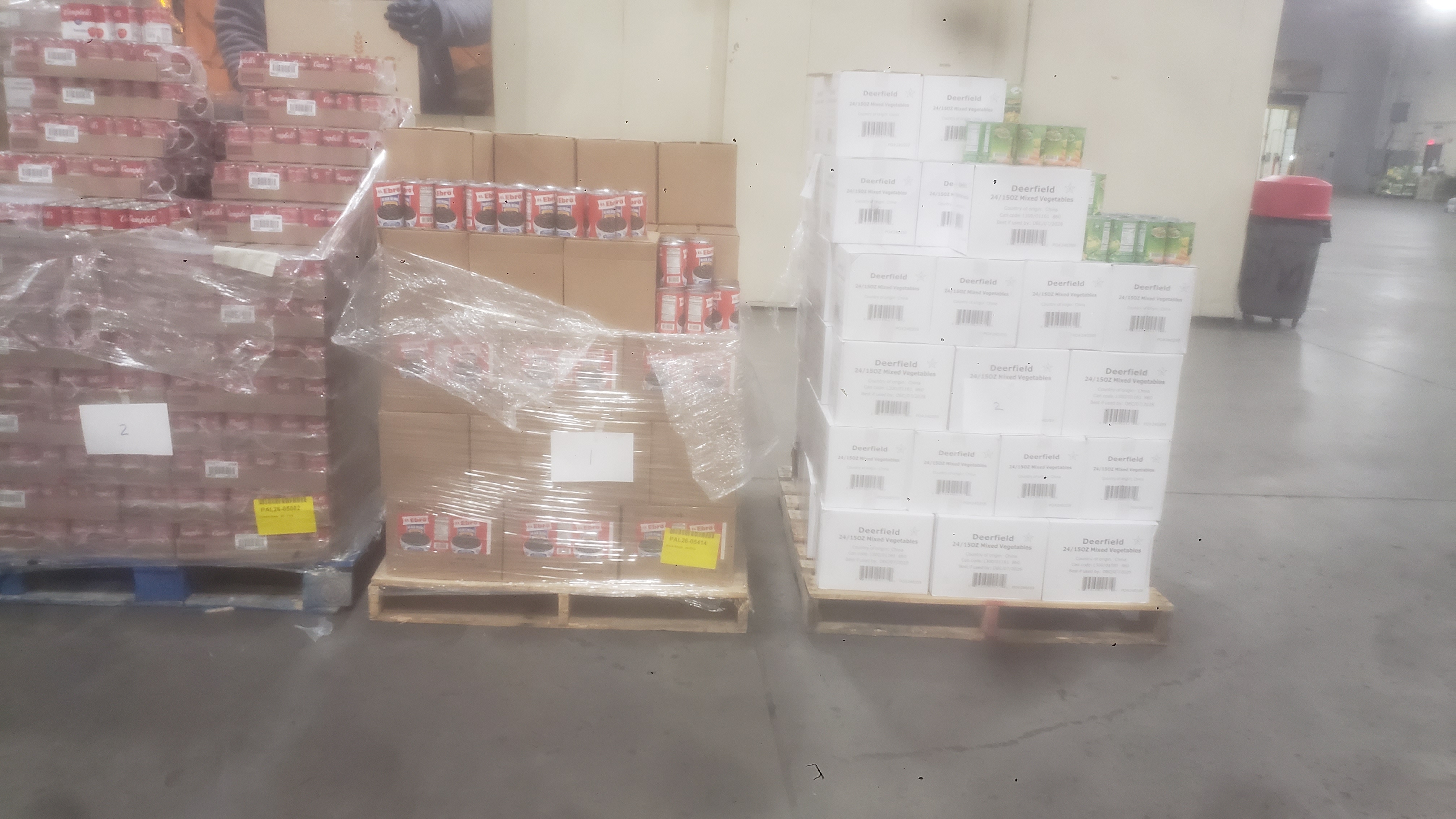 Boxes and trays of canned goods on pallets.